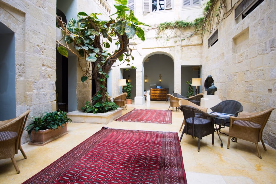 The limestone atrium at The Xara Palace, with a planted courtyard and seating beneath tall windows